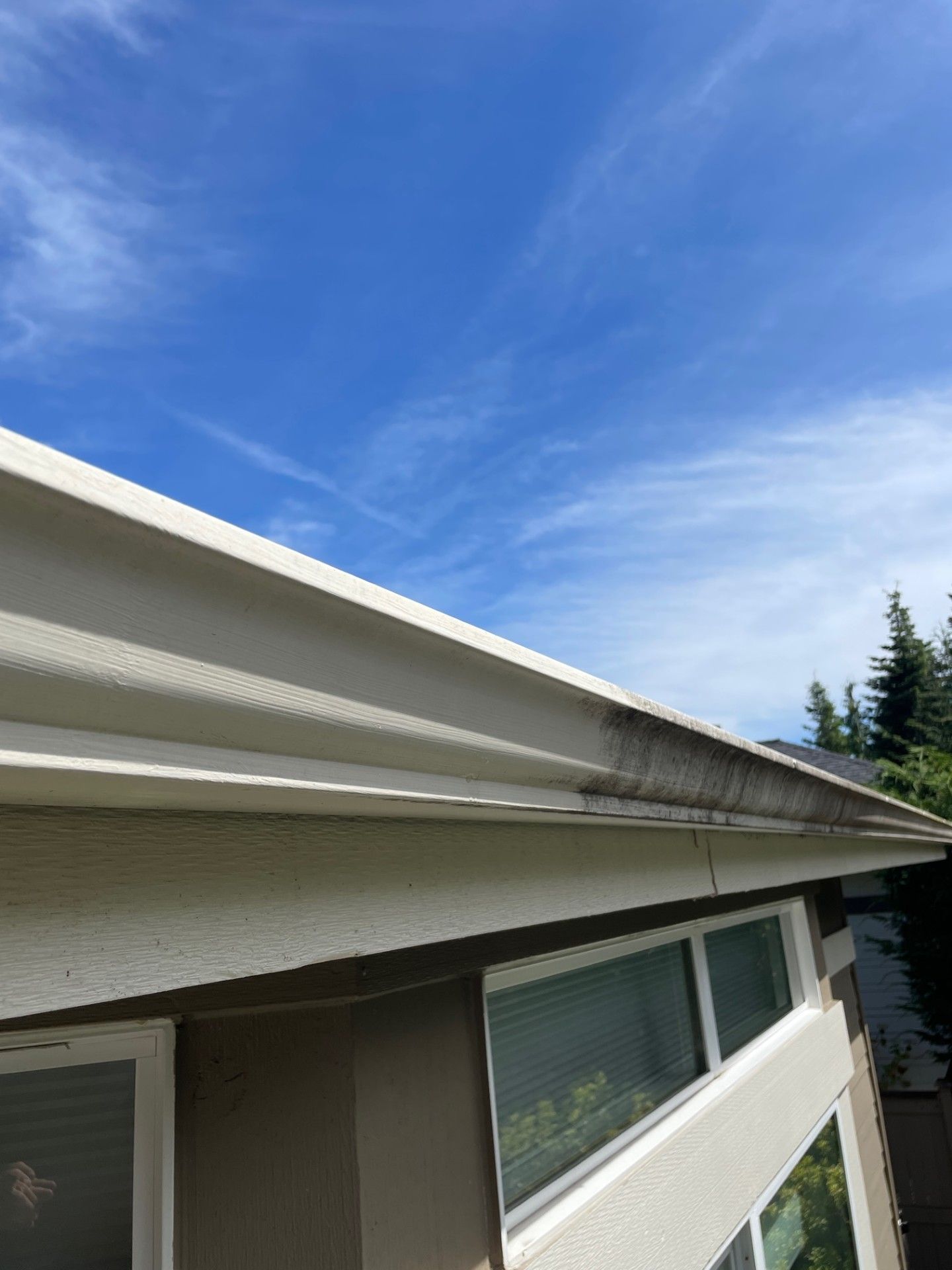 A gutter on the side of a house with a blue sky in the background.