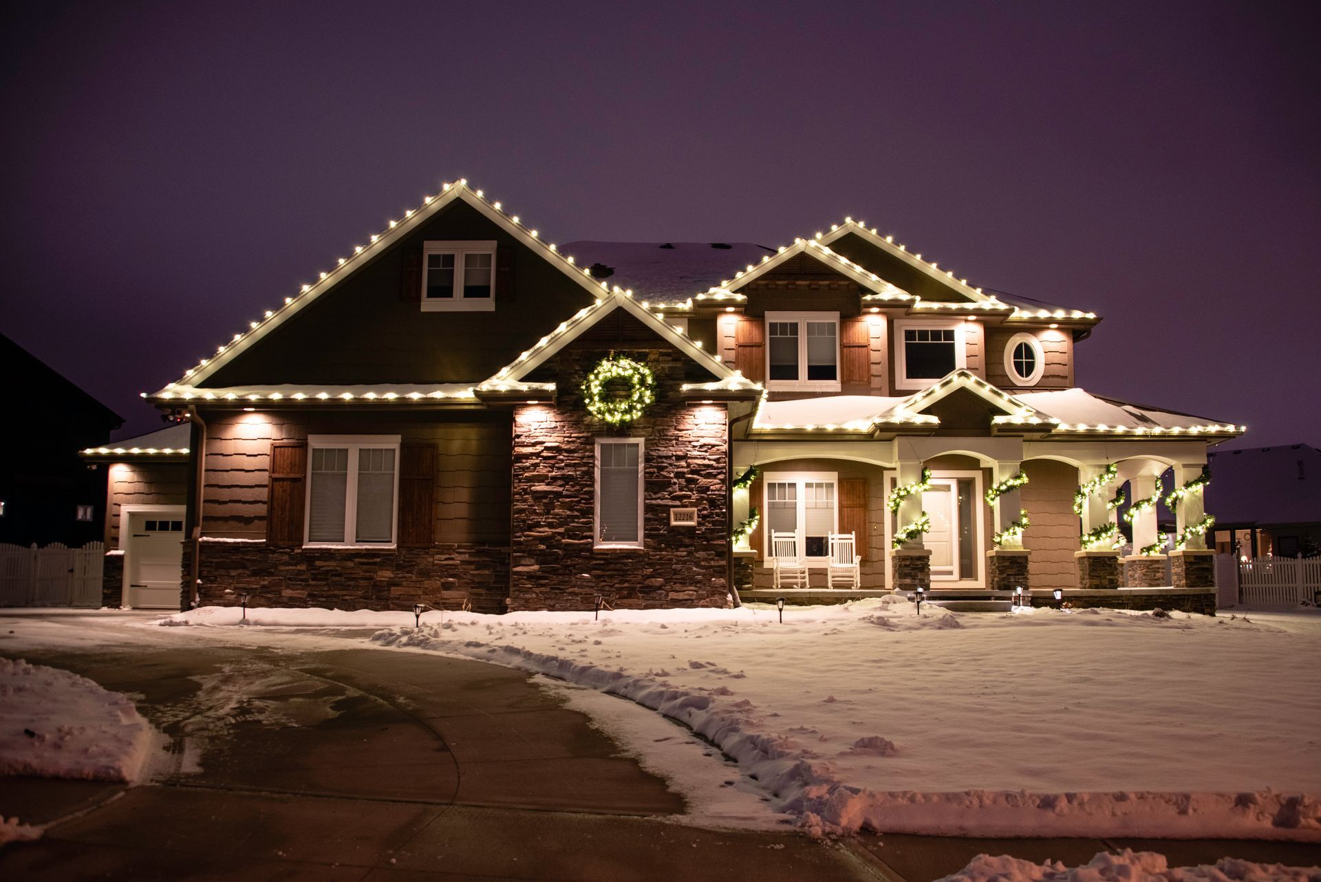 A large house is decorated with christmas lights and a wreath.