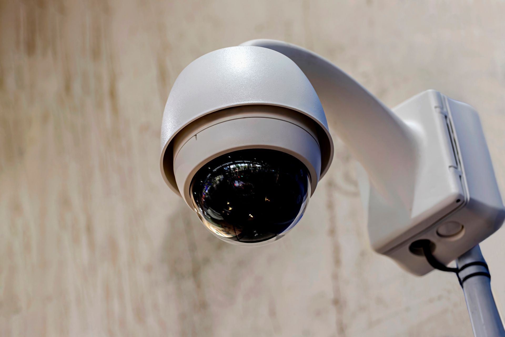 Close-up of a modern security camera mounted on a wall, featuring a dome-shaped lens.