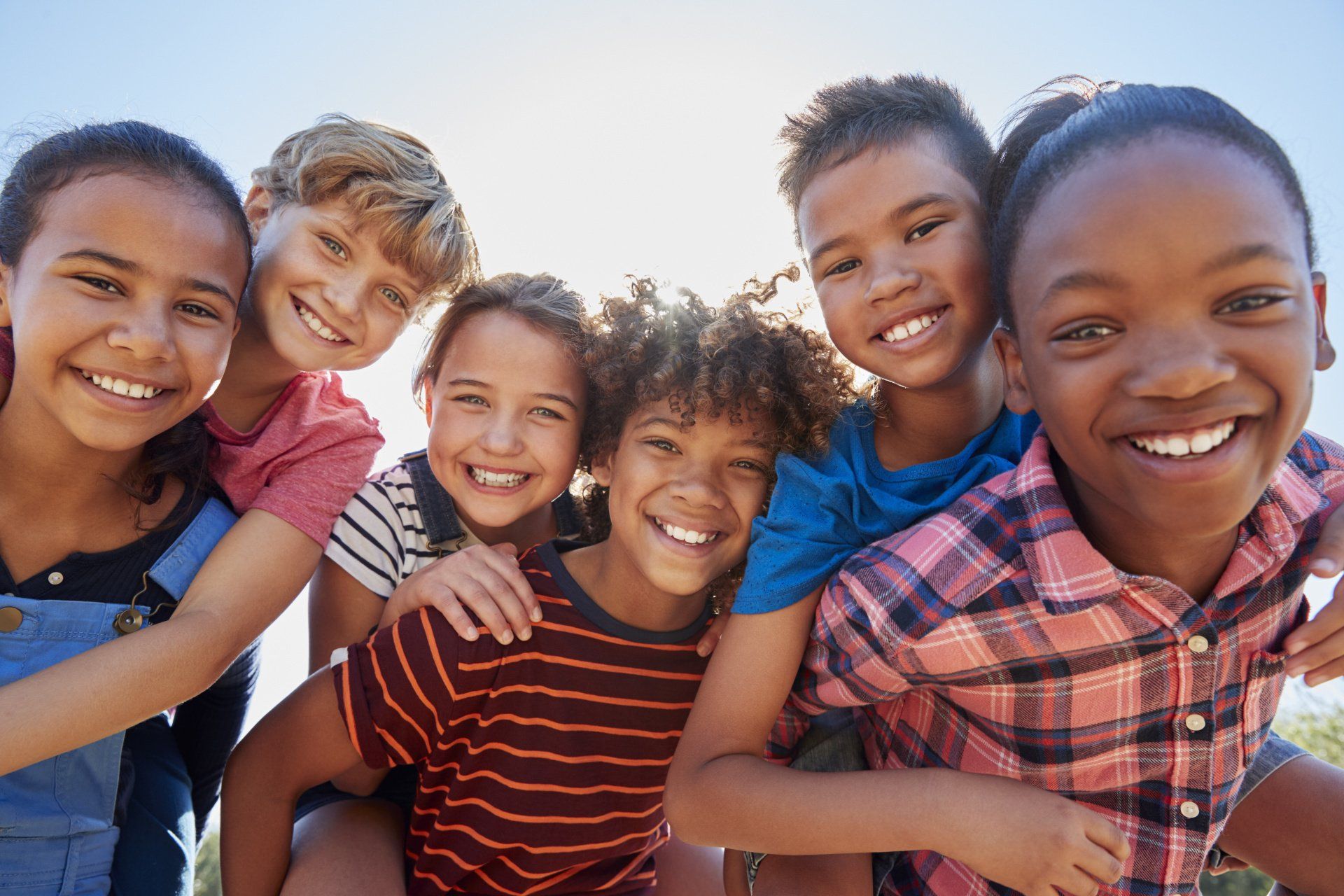A group of children are posing for a picture together and smiling.