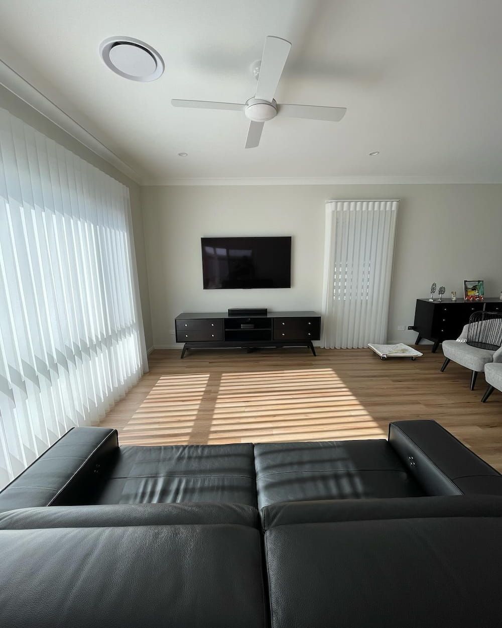 A Living Room With A Black Couch And A Newly Installed Flat Screen Tv On The Wall — KARM Electrical Services In Medowie, NSW