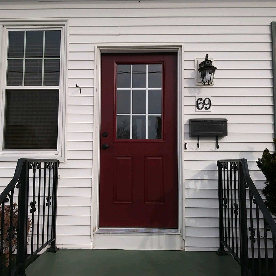 A white house with a red door and the number 69