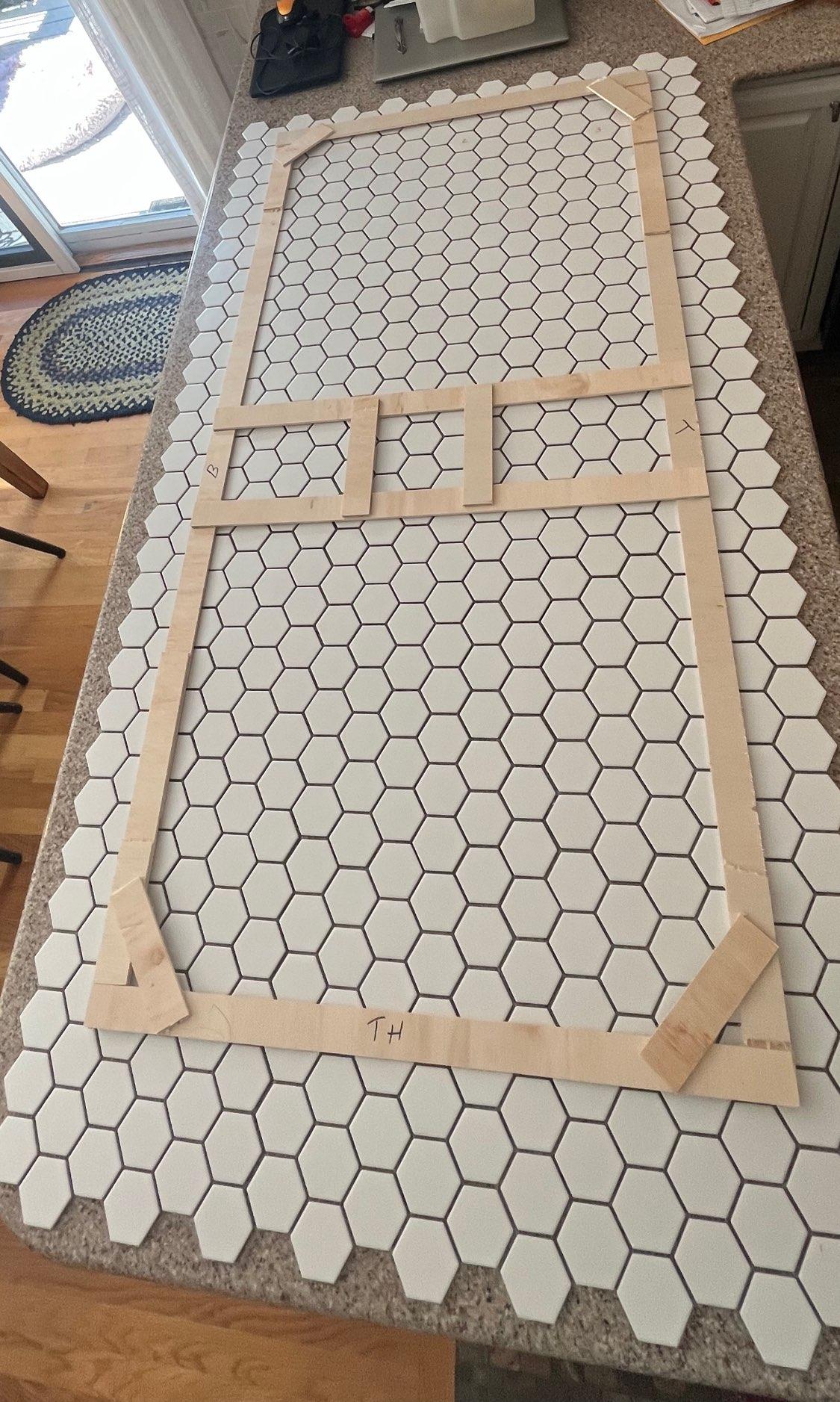 A wooden frame is sitting on top of a tiled counter top.