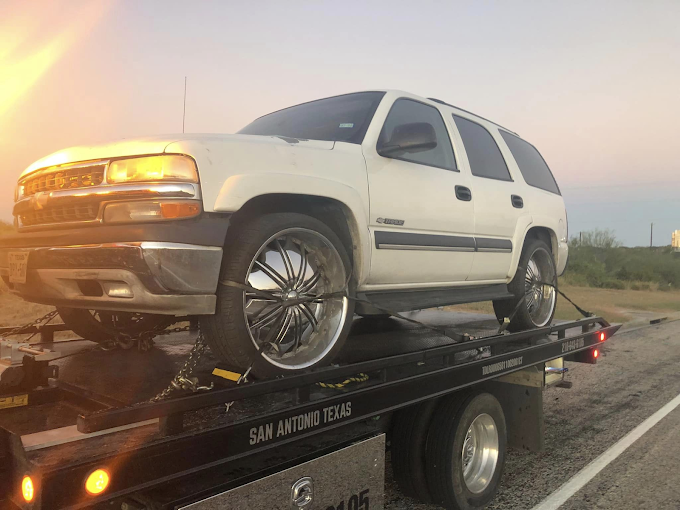 A white suv is sitting on top of a tow truck.