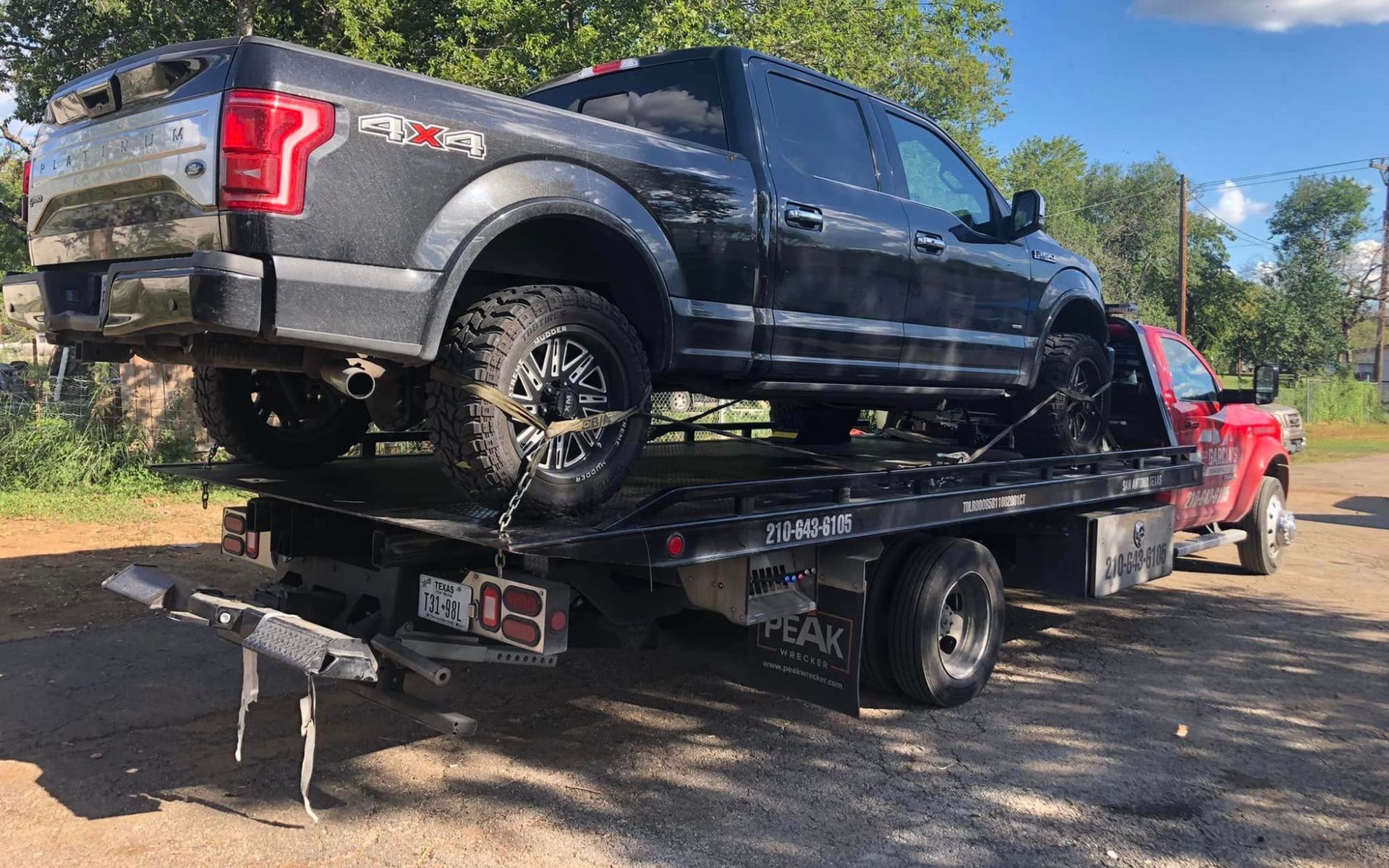 A black truck is sitting on top of a tow truck.