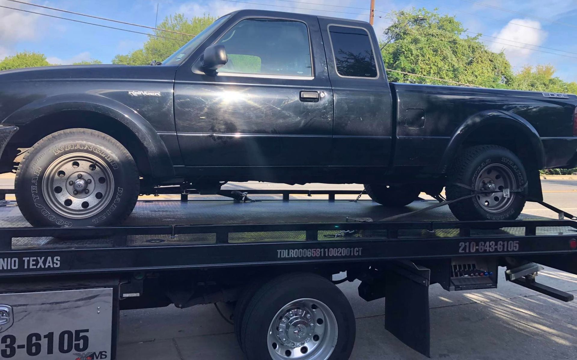 A black truck is sitting on top of a tow truck.