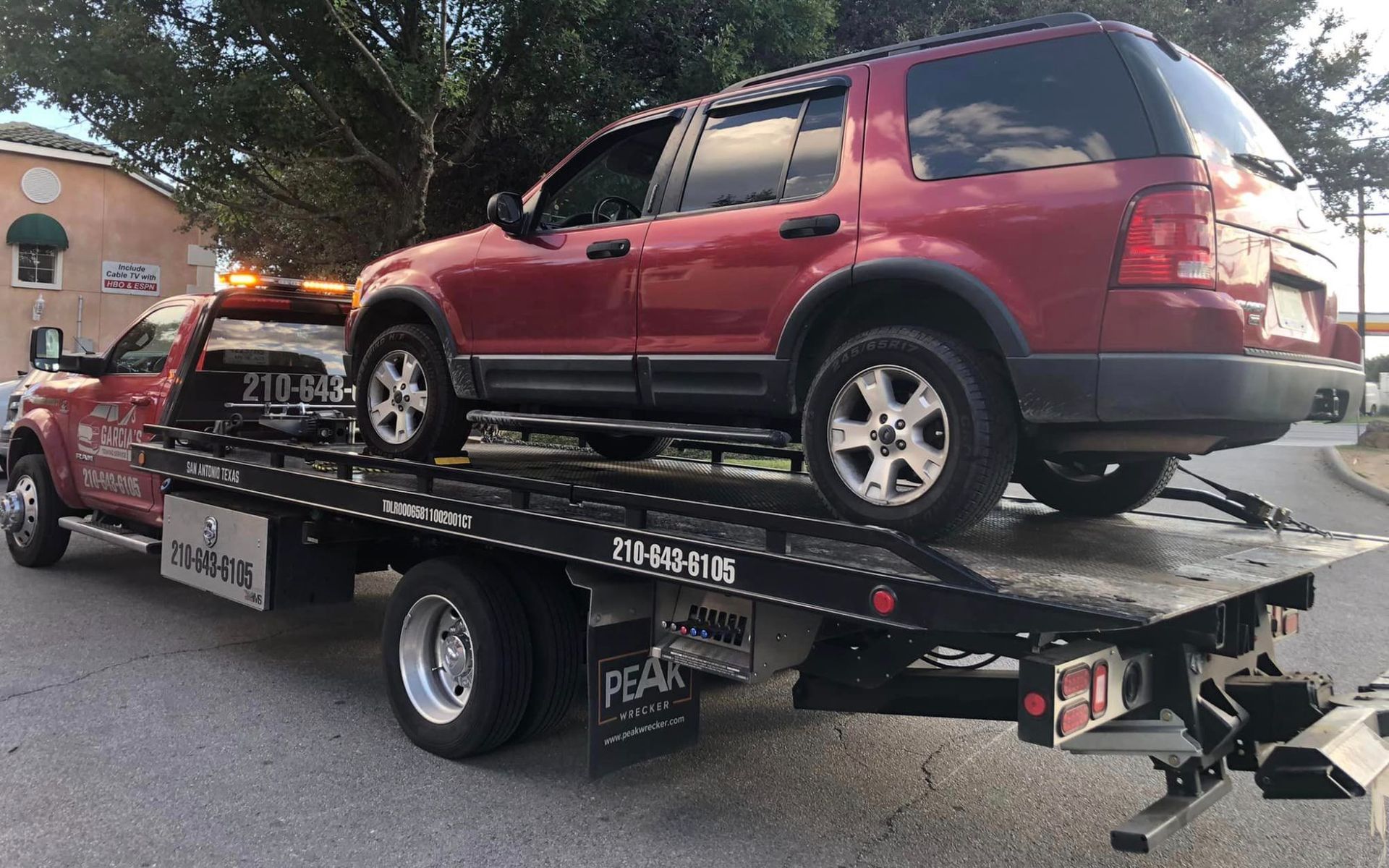 A red suv is being towed by a tow truck.