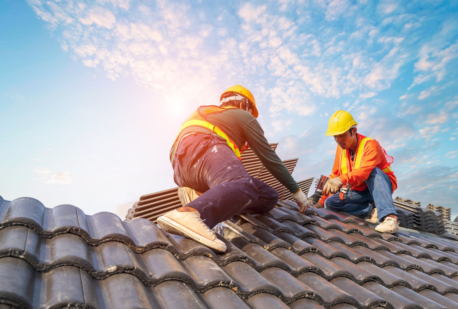 Two construction workers are working on the roof of a house.