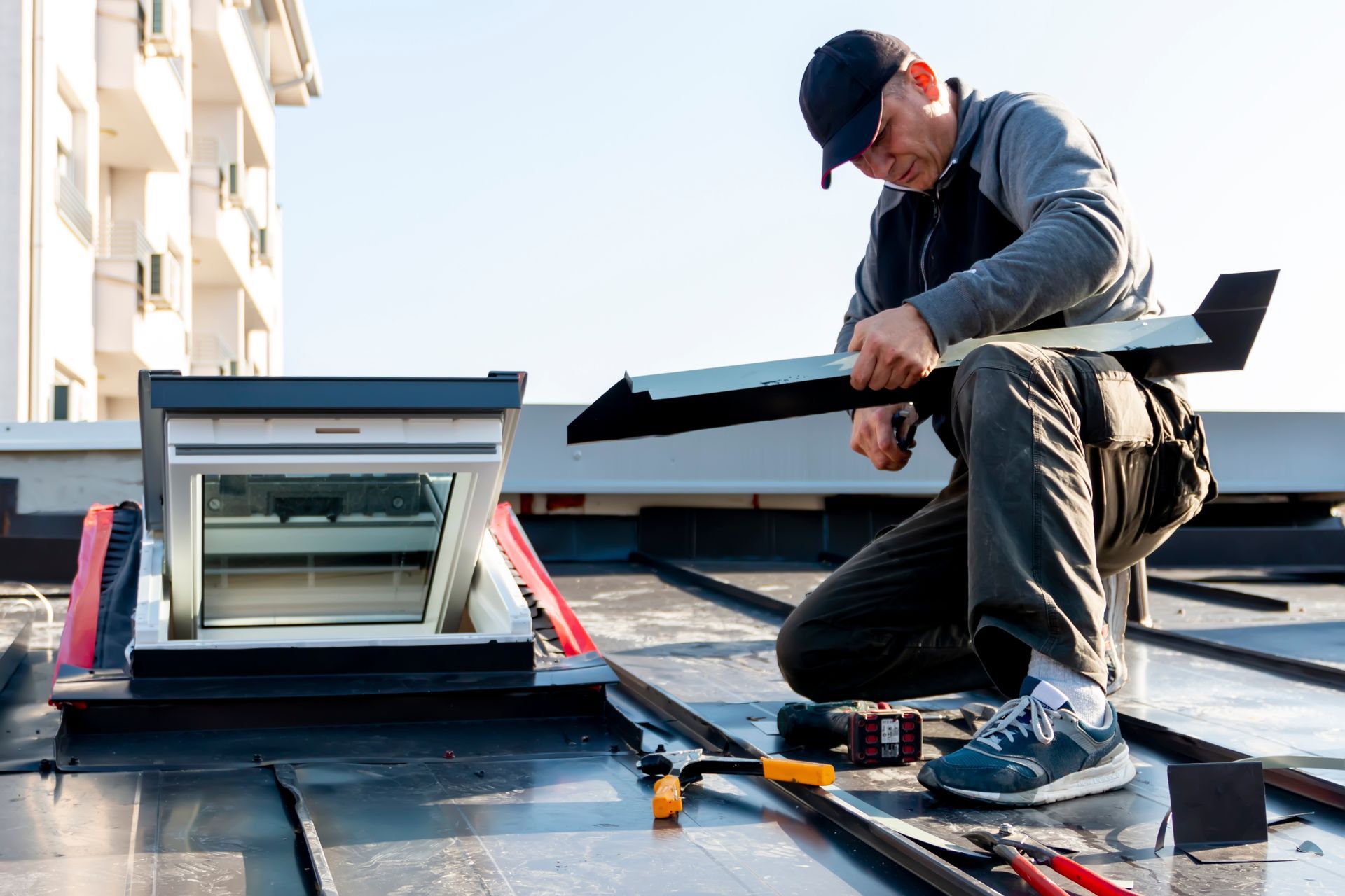 A man is working on a skylight on the roof of a building.