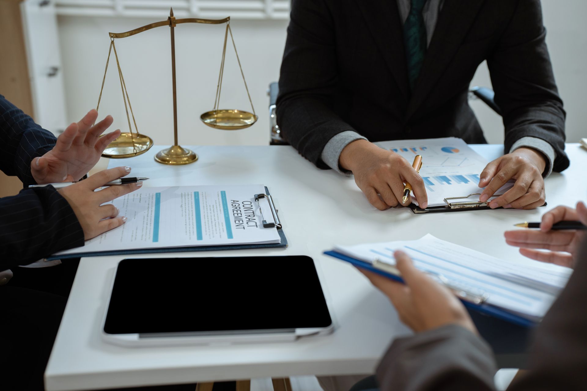 People at a table review documents, scales of justice in the background