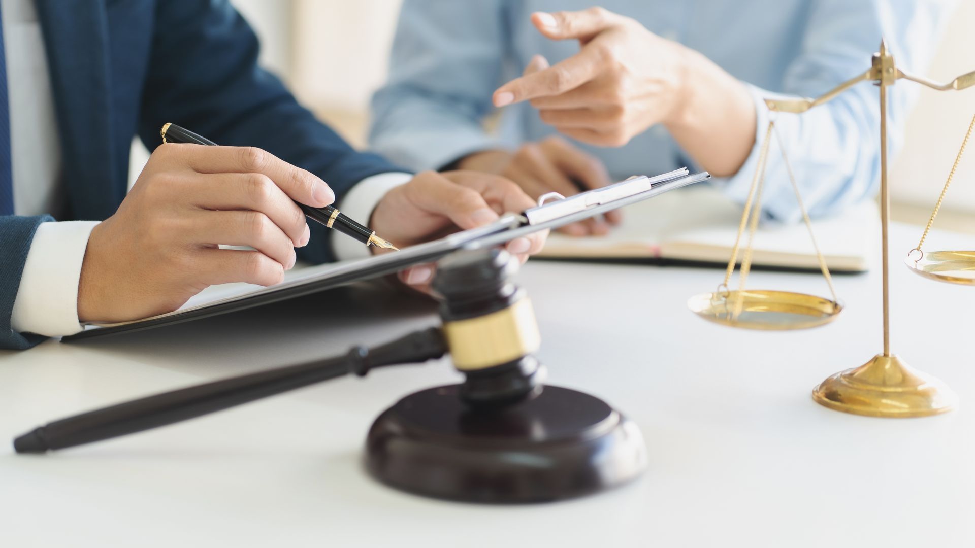 Attorney reviewing documents, with gavel and scales of justice on the table Attorney reviewing documents, with gavel and scales of justice on the table