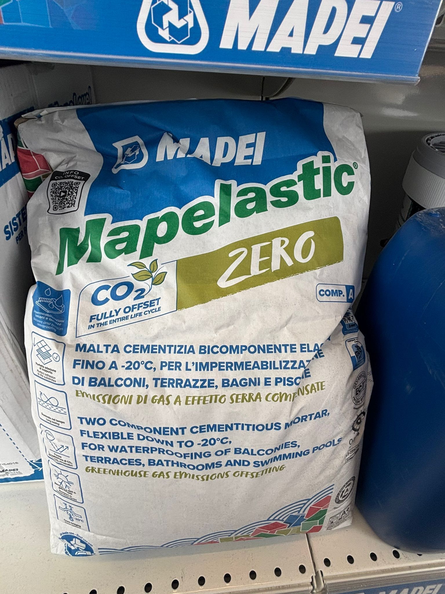 Pila di sacchetti bianchi e blu di adesivo MAPEI su sfondo scuro