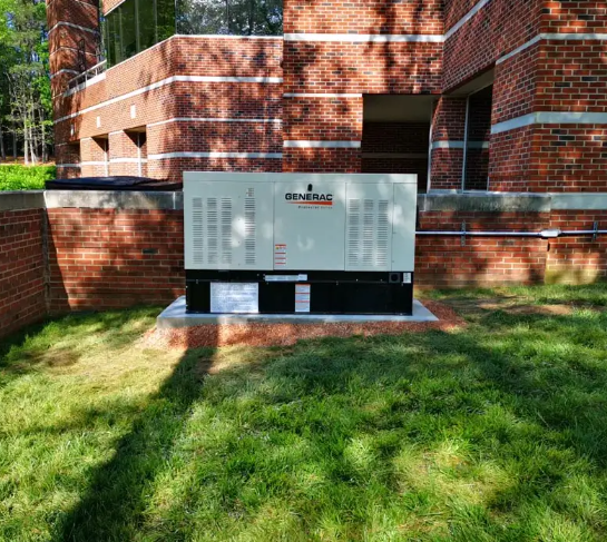Generator against a brick building; grassy area in the foreground.