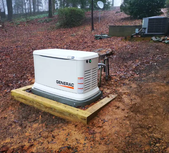 White Generac generator on a wooden base in a muddy yard, near a house with an air conditioner.