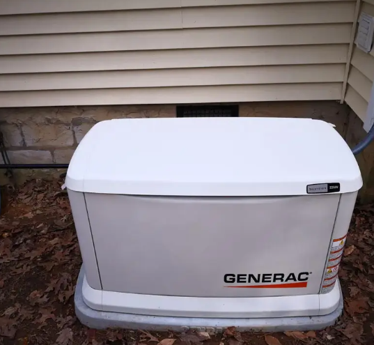 A Generac generator outside a building with tan siding.