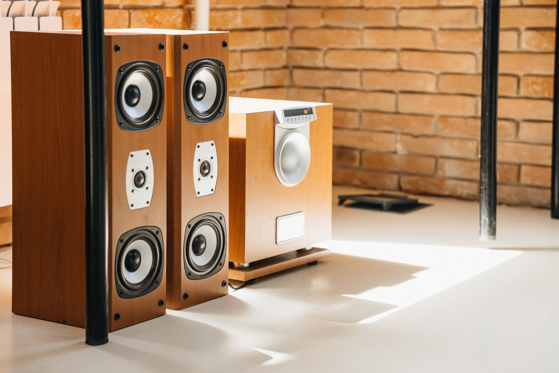 Wooden speakers set up in a room with a brick wall.