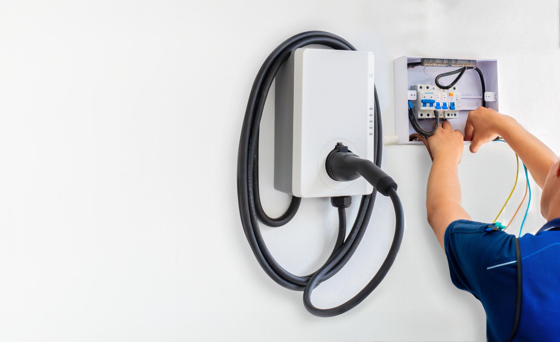 Person wiring an EV charger on a white wall. 