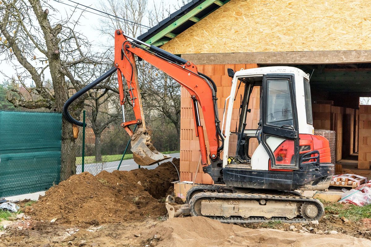 Orange excavator digging in front of a building under construction.
