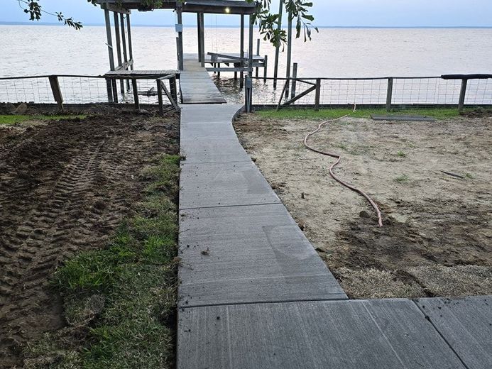 A concrete walkway leading to a dock next to a body of water.