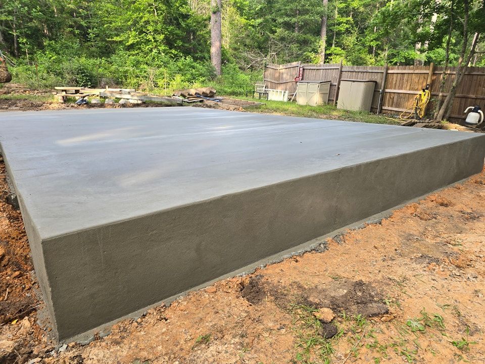 A large concrete slab is sitting in the middle of a dirt field.