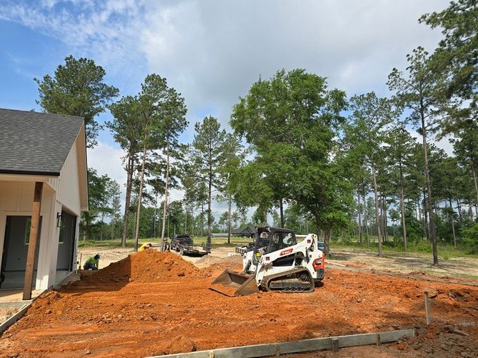 A bulldozer is moving dirt in front of a house.