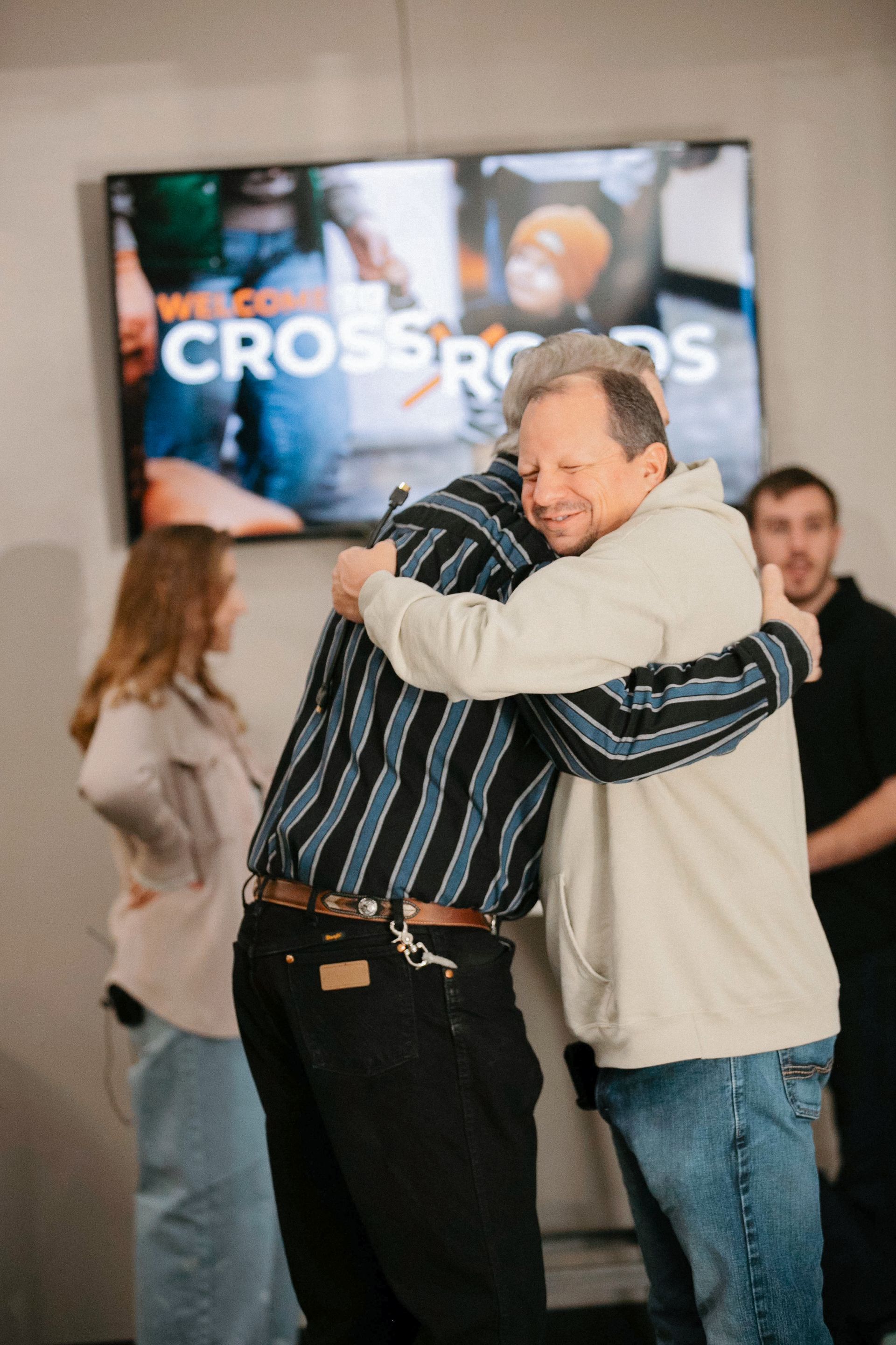 A group of people are praying together in a huddle in a dark room.