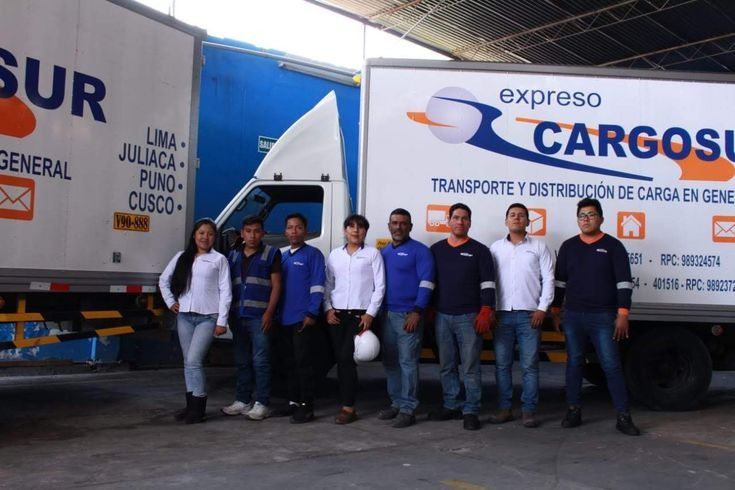 Un grupo de personas de pie frente a camiones de carga exprés.