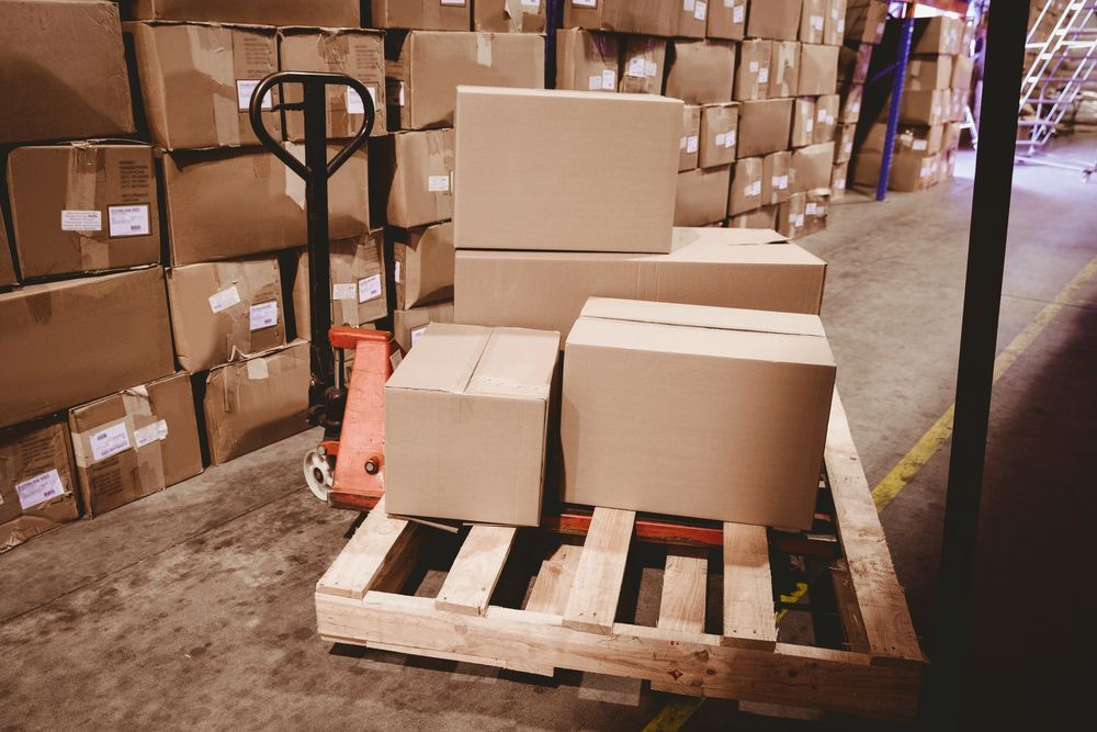 Un montón de cajas de cartón están apiladas una encima de otra en un almacén.