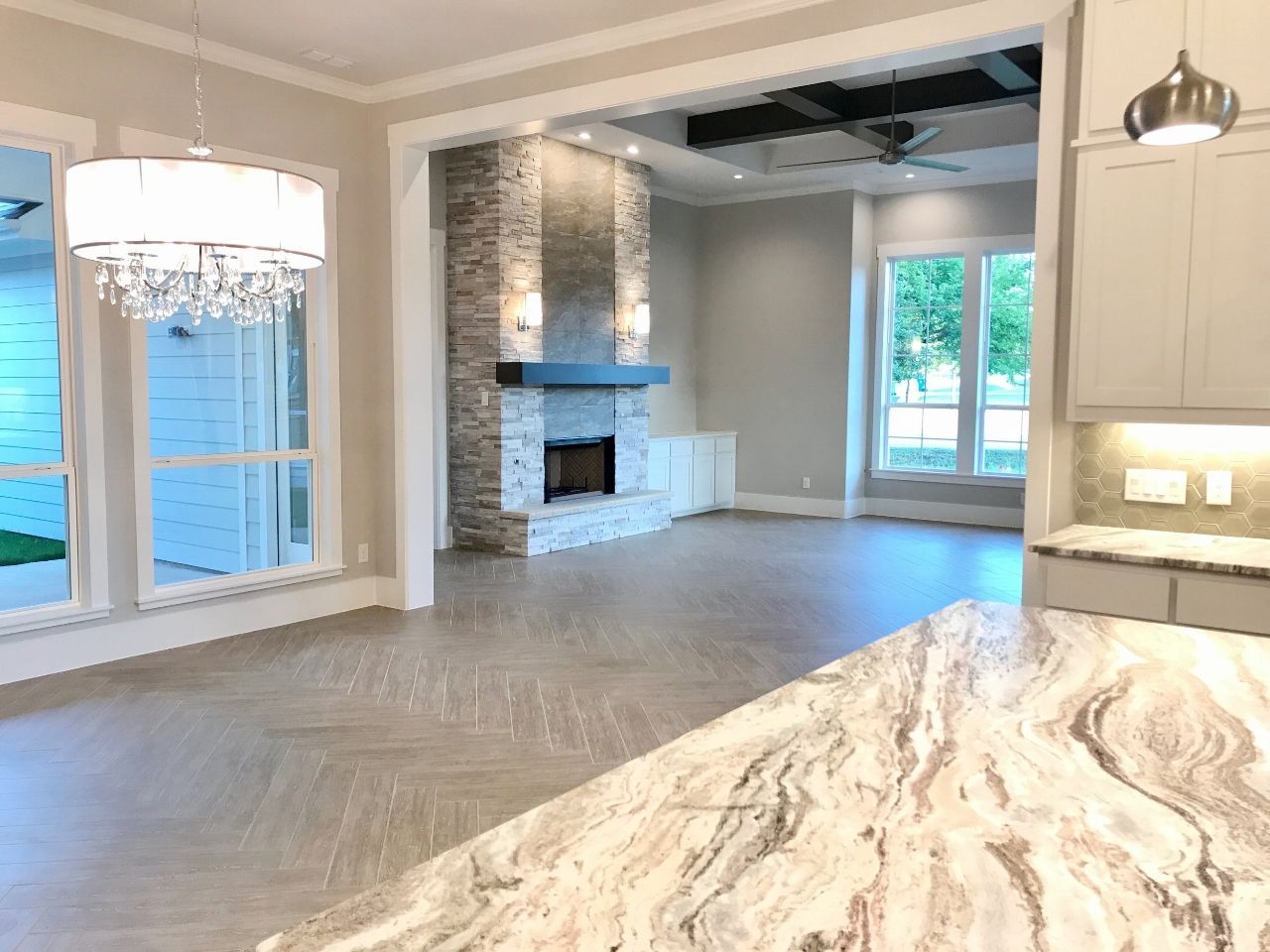Spacious interior with stone fireplace, hardwood floors, and granite countertop; neutral tones.