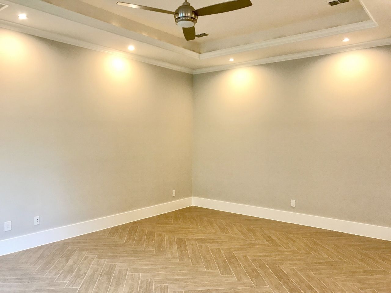 Empty room with beige walls, white trim, recessed lighting, and wooden floor.
