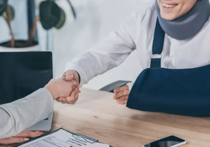 A person sitting in a wheelchair smiles during an interview, gesturing while speaking to someone holding a resume.