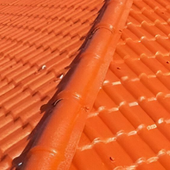Primer plano de un tejado de tejas de color naranja con una cumbrera central.