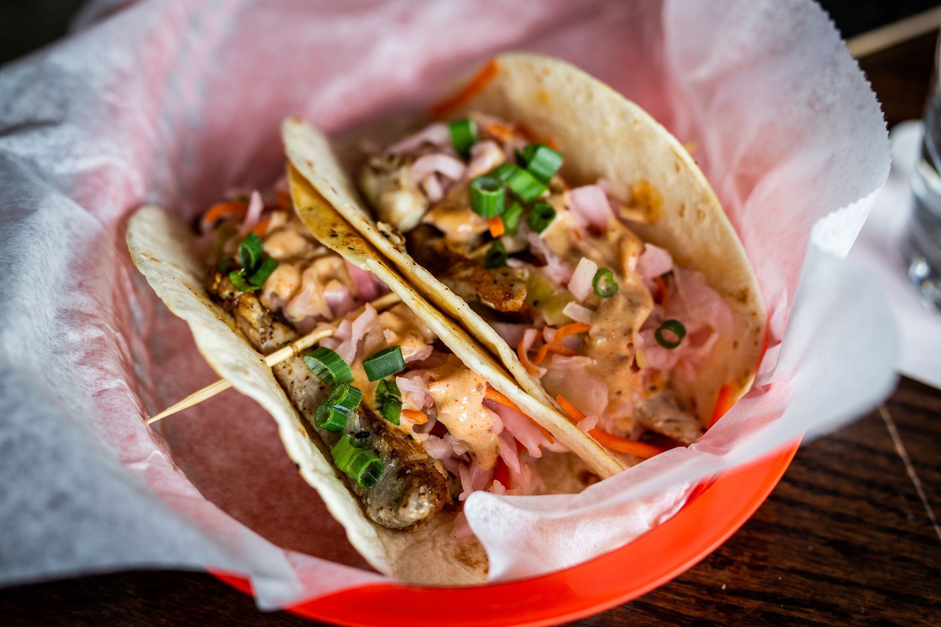 A close up of two tacos in a basket on a table.