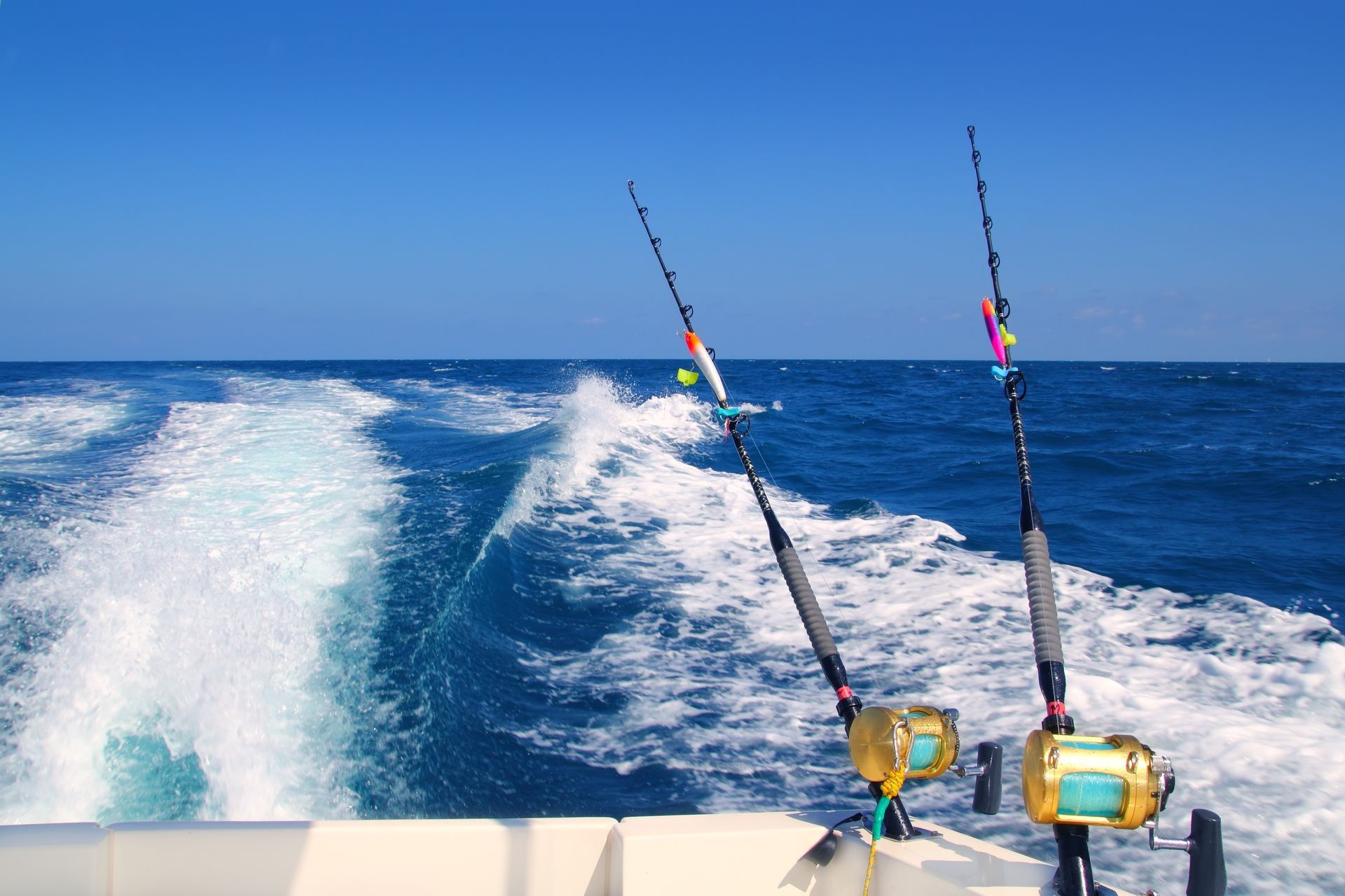 Two fishing rods are on the back of a boat in the ocean