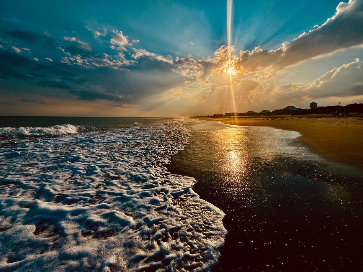 The sun is shining through the clouds on the beach