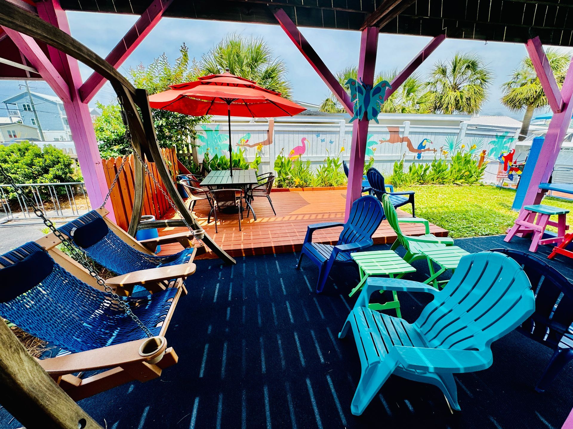 A patio with a hammock , chairs , tables and umbrellas