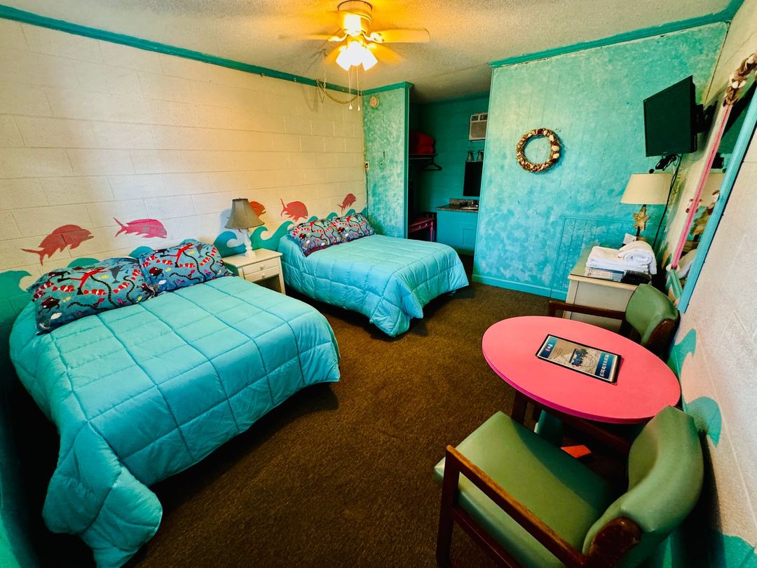 A hotel room with two beds and a pink table