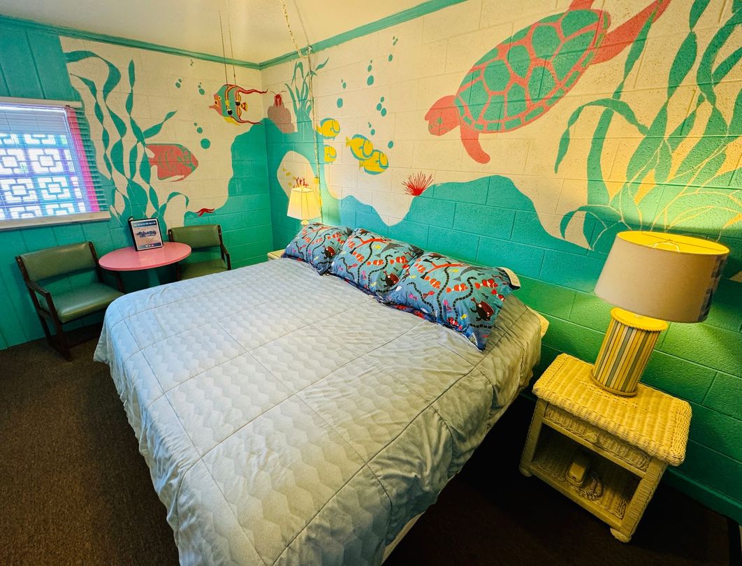 A bedroom with a bed and a painting of a turtle on the wall.