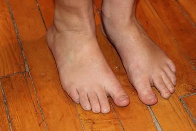 A person 's bare feet are standing on a wooden floor.