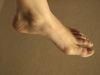 A close up of a person 's foot on a brown surface.