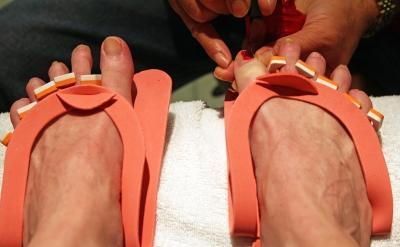 A woman is getting her toes painted in a salon while wearing flip flops.