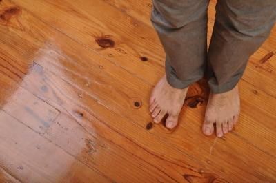 A person 's bare feet are standing on a wooden floor.