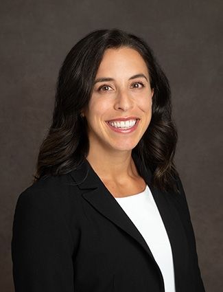 A smiling doctor in a lab coat with a stethoscope around his neck.