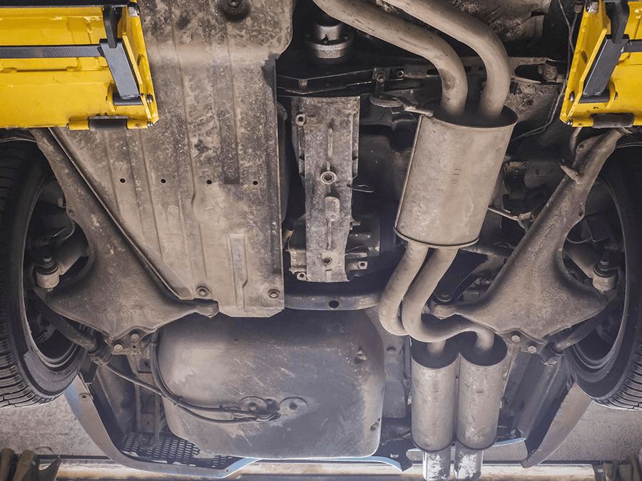 A close up of the underside of a car with exhaust pipes