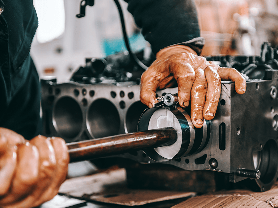 A man is working on a car engine with a wrench.