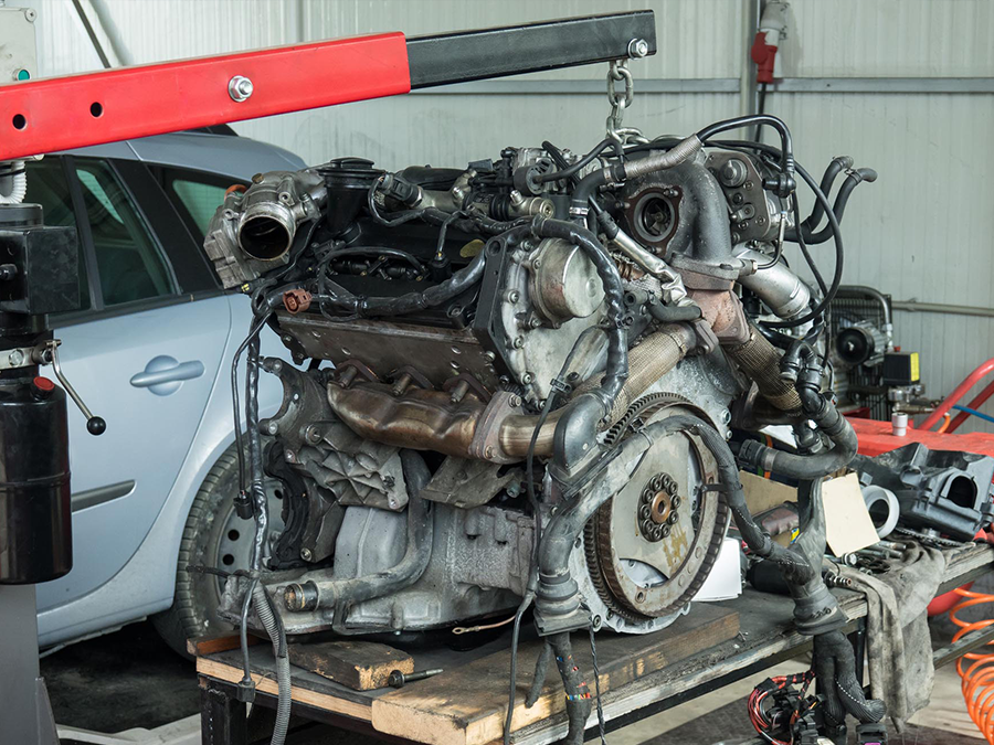 A car engine is being dismantled in a garage.