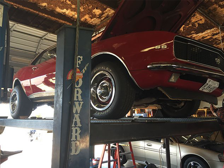 A red car is on a lift with the word forward on it