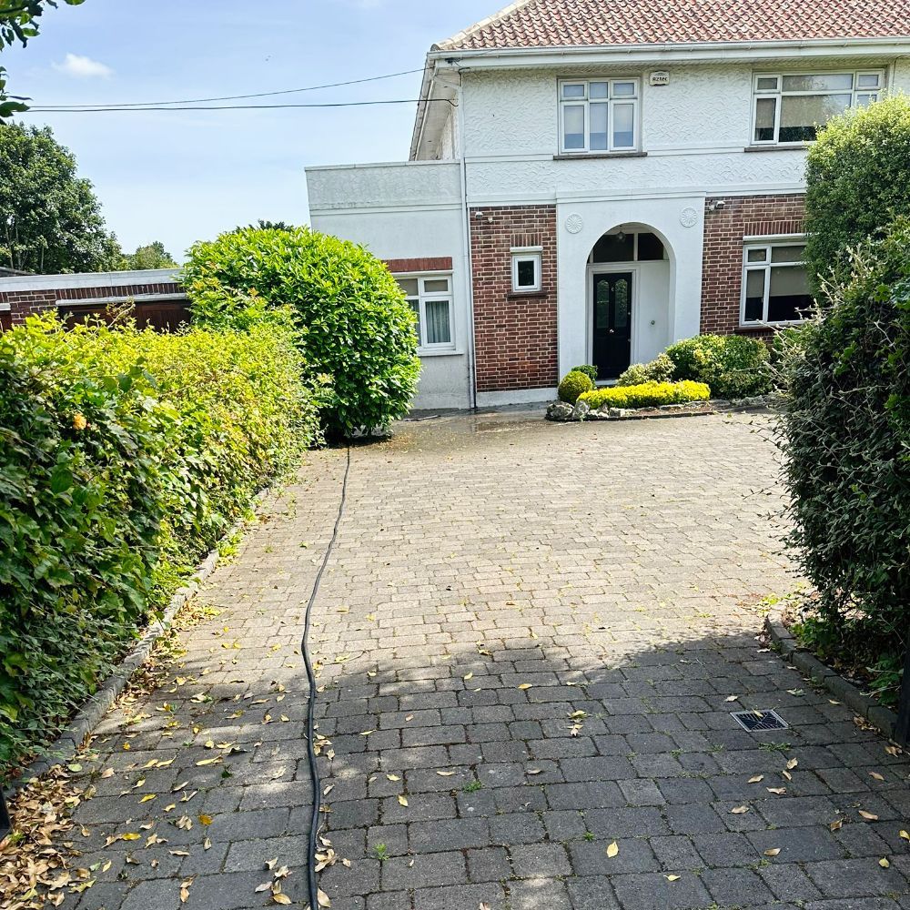 A brick driveway leading to a white house