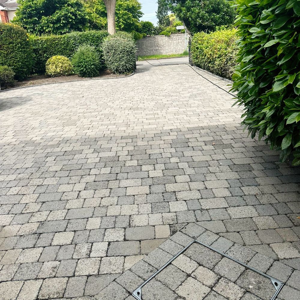 A brick driveway with a manhole cover in the middle of it.