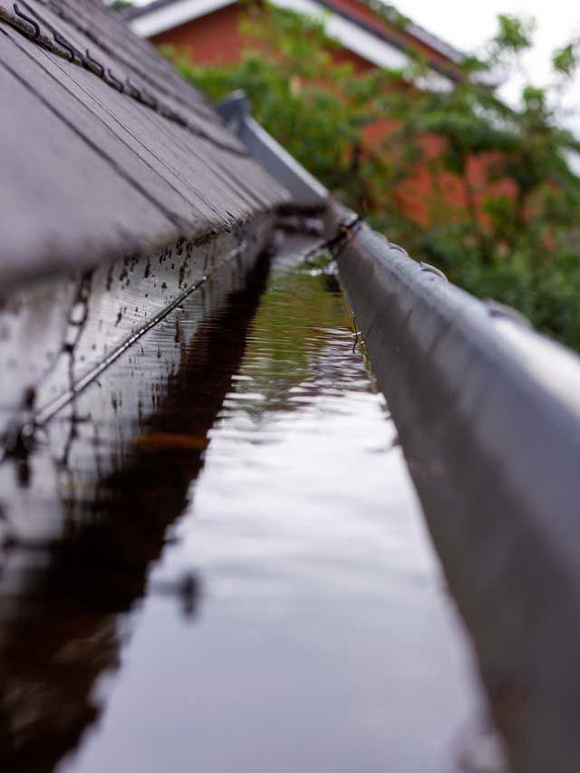 A close up of a gutter with water coming out of it.